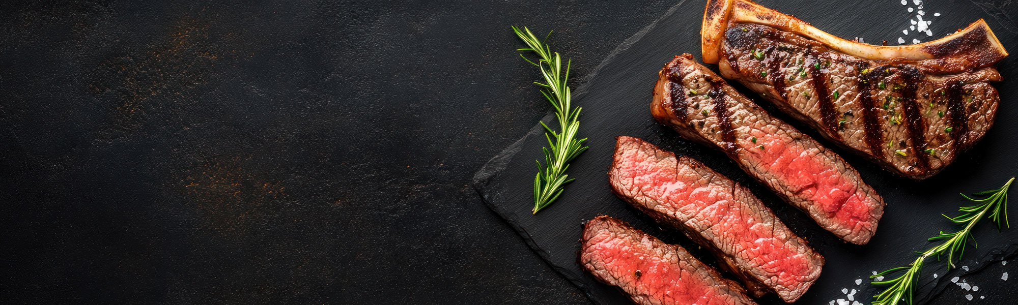 Grilled Steak With Bone And Rosemary On Black Slate